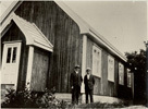 Bilde av Filadelfias første lokaler, trehus med to personer stående foran
